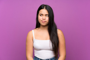 Young teenager Asian girl over isolated purple background standing and looking to the side