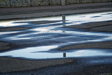 Sky reflected in a puddle of water on pavement, Early morning sunrise. - 286137654