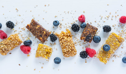 Pattern with cereal bars and blueberries, blackberries and raspberries with oatmeal. Healthy snacks and breakfasts