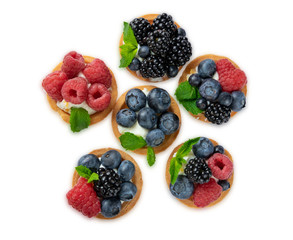 Tartlet with berries of raspberry, bilberry, blackberry, blueberry isolated on white background. Cake with berries, mint leaf and cheese cream. View from above