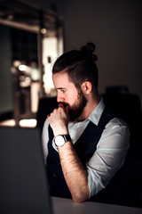 A portrait of young businessman with computer in an office, working.
