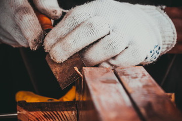 The hand of the carpenter taking the chisel to sharpen the wood plank