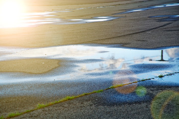 Sky reflected in a puddle of water on pavement, Early morning sunrise.