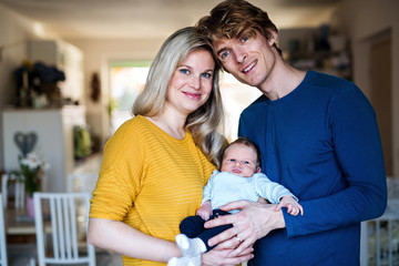 Fototapeta premium Beautiful young parents with a newborn baby at home.