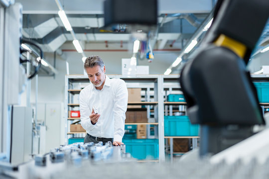 Businessman in a modern factory holding workpiece