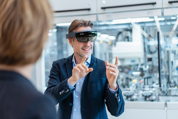 Businessman with AR glasses and businesswoman in a modern factory