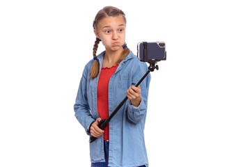 Portrait of beautiful happy teen girl making selfie with stick. Teenager posing to smartphone on selfie stick, isolated on white background. Child taking selfie on mobile phone for social network.