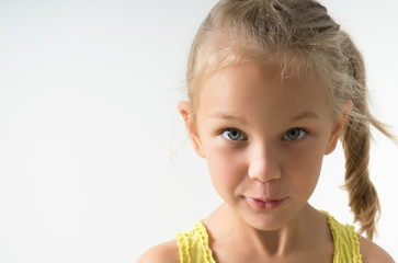 little blonde girl of 5 years old looks inquiringly in surprise at the frame, closeup isolated on a light background