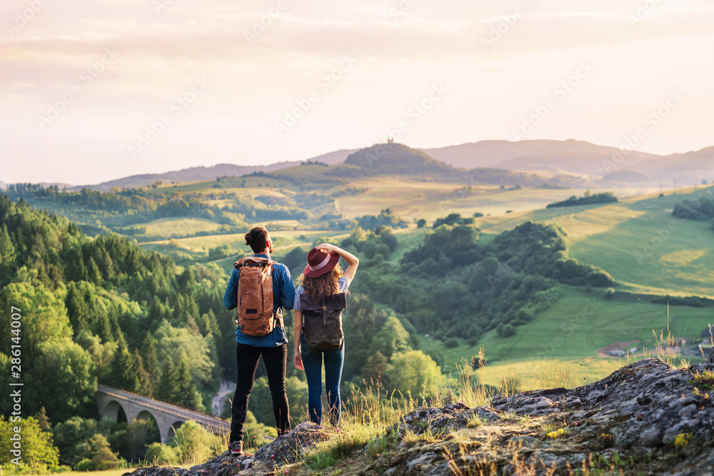 Wall mural rear view of young tourist couple travellers hiking in nature, resting.