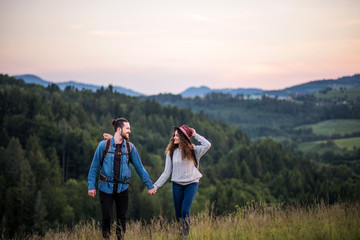 Young tourist couple travellers with backpacks hiking in nature.