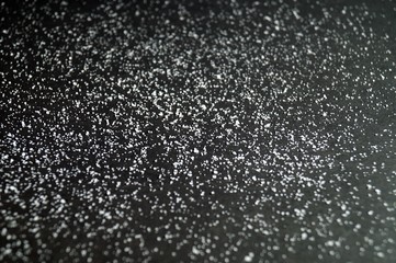 background of Rough Uneven Crystals of shallow salt on a dark gray and black table. Abstract Grunge. Background for advertising salt. Salted food. concept excessive salt intake. selective focus.