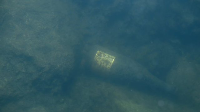 Old glass wine bottle underwater on sea or lake floor