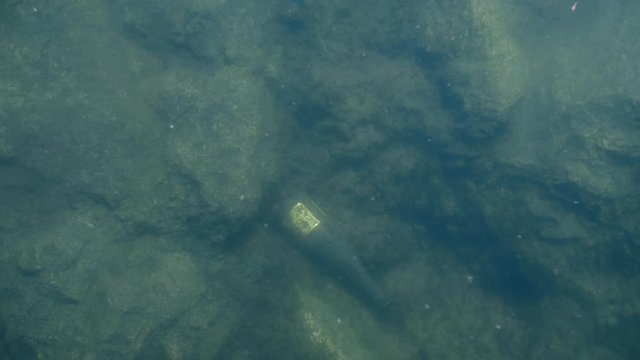 Old glass wine bottle underwater on sea or lake floor