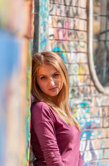 Naklejka premium Outdoors portrait of a woman, leaning against a colored wall