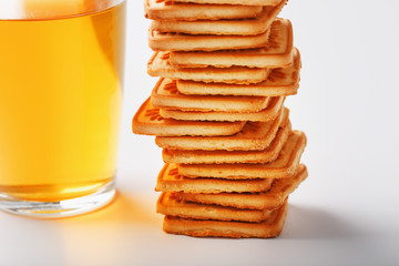 A stack of golden wheat cookies and a mug of fragrant green tea in on a white background. Cookies laid out in a breakfast column and a golden highlight with tea mugs