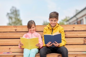 education, childhood and people concept - happy school children or brother and sister reading books...