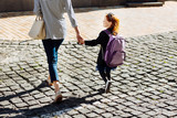 Beautiful schoolgirl holding hand of her mother