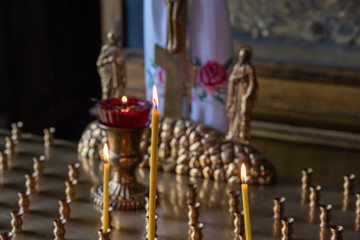 Thin burning candles and a lamp in a shackle in an Orthodox church.