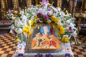 Icon decorated with a garland of white, red and yellow flowers.