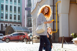 Pretty red-haired young mother walking with her daughter