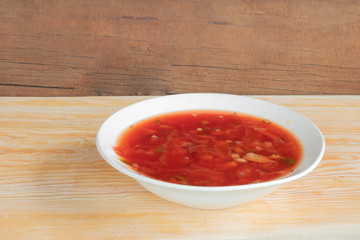 borsch in a white plate on a wooden background