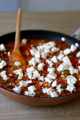 Pot of orzo pasta, with tomato sauce, vegetables and feta cheese. Selective focus.