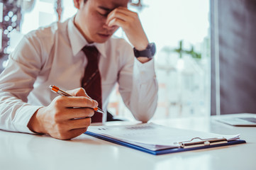 Businessmen feel stressed while looking at graph reports  sitting at his working place in office, finance business graph going down, mobbing concept