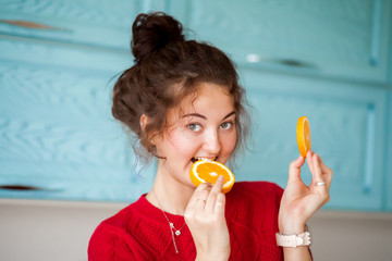 Cute girl eating an orange in the kitchen