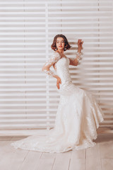 Young beautiful bride in a lace wedding dress in the studio on a striped background