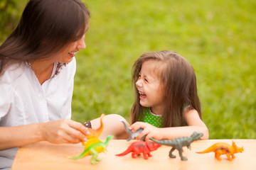 mother enjoys playing with her cute daughter in dinosaurs