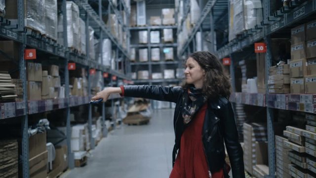 pretty girl dancing a wave with a phone in a large industrial stock room