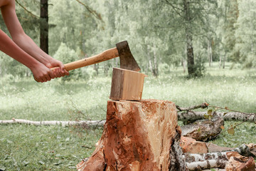 Hands of a man splitting wood with an axe