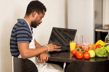 Man looking recipe on laptop in kitchen at home