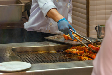 Close up photo of chef grilling lobsters in restaurant's kitchen