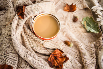 warm autumn. cup of coffee wrapped in a woolen beige sweater. still life.