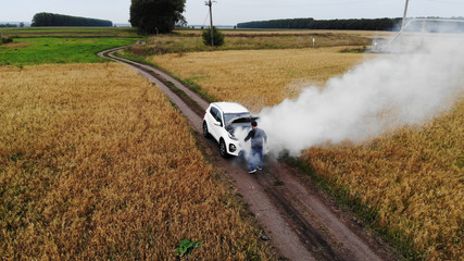 The car broke down, smokes from under the hood, the driver shocked.