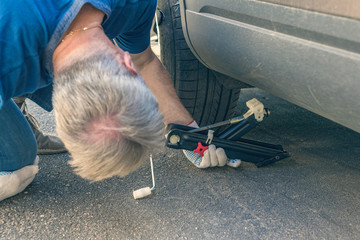 Men lifting a car with jack-screw for changing of punctured wheel. Hole in the tire. Concept