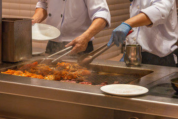 The restaurant chef cooking grilled lobsters on smoky electric stove
