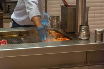 Asian chef cooking grilled lobster on electric stove in kitchen