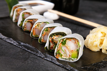 Close up view on served sushi rolls with crab on dark plate on dark background with copy space. Delicious rolls. Traditional Japanese cuisine
