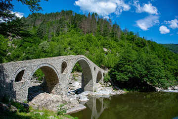 Fototapeta na wymiar Ancient roman bridge in the mountains with reflection in the water