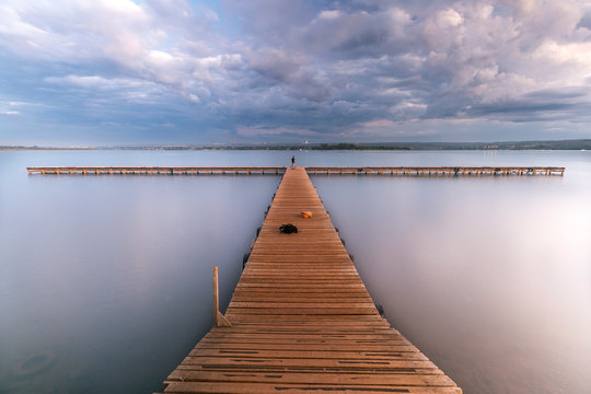 Fototapeta View of wooden pier over lake against cloudy sky