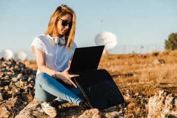 Young woman with her laptop communicates with antennas