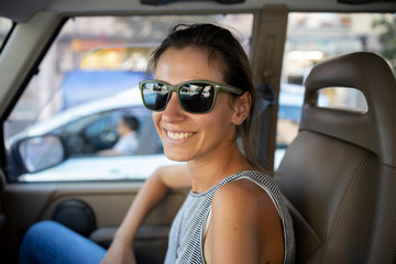 Young woman wearing sunglasses smiling in car
