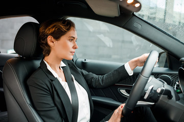 Businesswoman driving a car. Young female in formal wear holding a steering wheel.