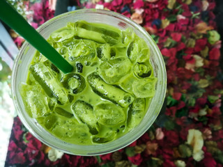 Green tea iced in plastic cup and green plastic tubes, Iced Green Tea Coffee Late or Matcha & Espresso Fusion on colorfull flowers background.