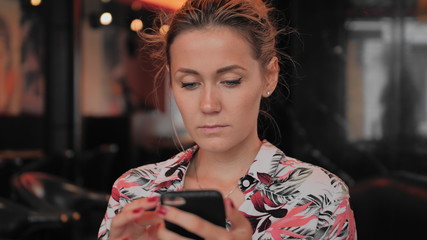 Caucasian young female uses smartphone while sitting in a restaurant. Slow Motion.