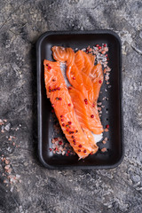 Raw fillet of salmon. Fresh salted and beautiful salmon fillet on black plate. Delicious fish meat