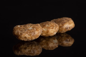Group of three whole chocolate ball breakfast cereals in row isolated on black glass