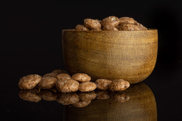 Lot of whole crispy chocolate ball breakfast cereals in wooden bowl isolated on black glass